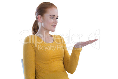 Young businesswoman holding imaginary product while sitting on chair