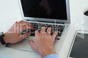 Cropped hands of businessman using laptop by tablet computer