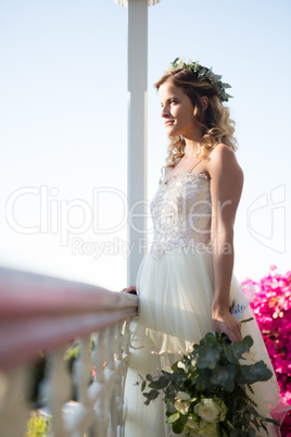 Beautiful bride holding bouquet while standing in balcony