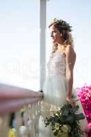 Beautiful bride holding bouquet while standing in balcony