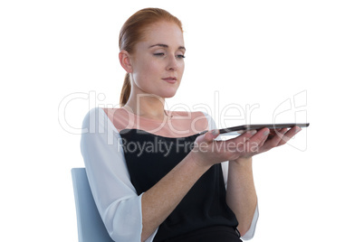 Businesswoman holding tablet computer while sitting on chair