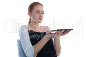 Businesswoman holding tablet computer while sitting on chair