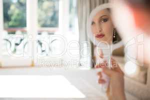 Bride looking into hand mirror at home