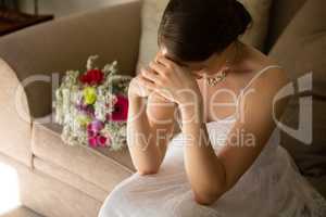 High angle view of upset bride sitting by bouquet on sofa