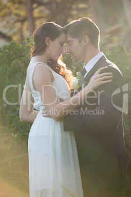 Romantic newlywed couple with eyes closed standing at park