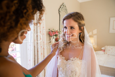 Beautician dressing up bride at home