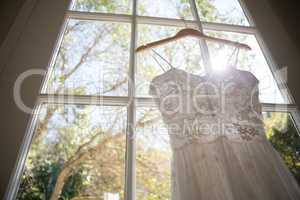 Low angle view of wedding dress hanging on window in room