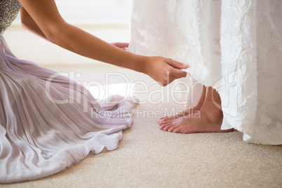 Midsection of bridesmaid assisting bride in getting ready