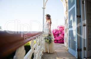 Pretty bride holding bouquet while standing in balcony