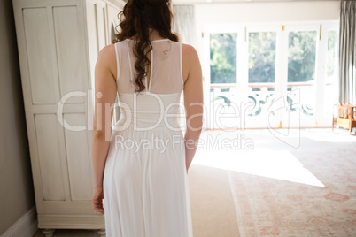 Bride in wedding gown standing at home