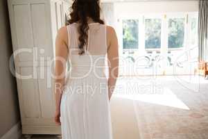 Bride in wedding gown standing at home