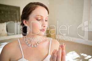 Beautiful bride looking wedding ring while sitting on bed