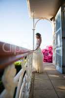 Beautiful bride standing by railing in balcony