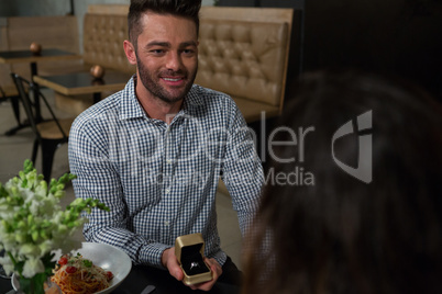 Man proposing woman while having dining