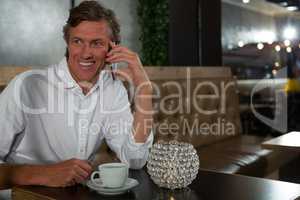 Man talking on mobile phone while having coffee