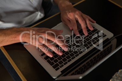 Mid section of man using laptop at table
