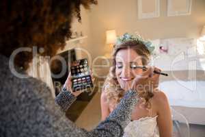 Woman applying makeup to bride in dressing room