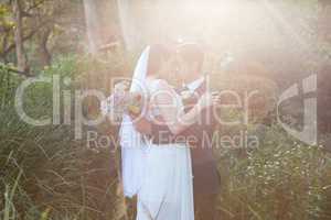 Romantic newlywed couple with eyes closed embracing in park