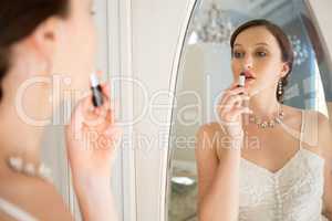 Side view of beautiful bride applying lipstick reflecting on mirror