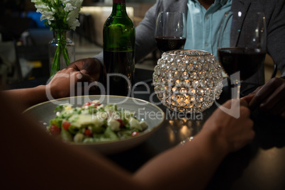 Couple holding hands while dining at table