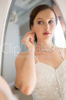 Mirror with reflection of beautiful bride wearing earring