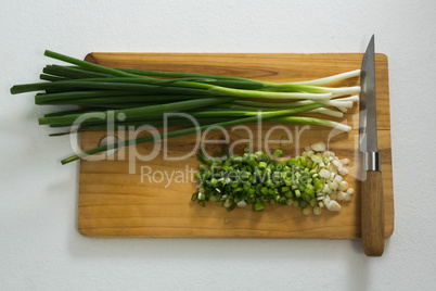 Chopped scallions with knife on chopping board