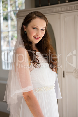 Portrait of happy bride in wedding dress at home