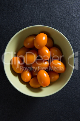 Tomatoes in bowl on black background