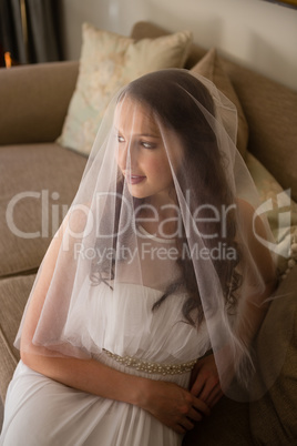 High angle view of beautiful bride in wedding dress sitting on sofa