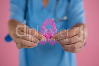 Mid section of female doctor in scrubs showing Breast Cancer Awareness ribbon