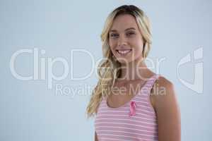 Portrait of smiling young female in tank top with pink ribbon