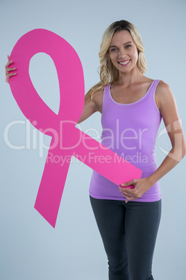 Portrait of young female showing cardboard Breast Cancer Awareness ribbon