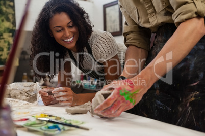 Mid section of man assisting woman in molding clay