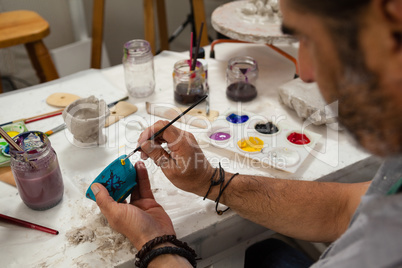 Attentive man painting bowl