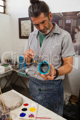 Attentive man painting bowl