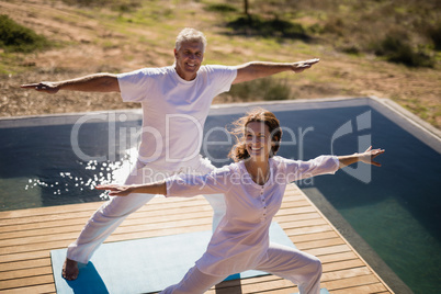 Portrait of happy couple practicing yoga on at poolside