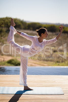 Woman practicing yoga on at poolside