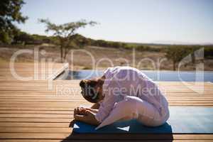 Woman practicing yoga on at poolside