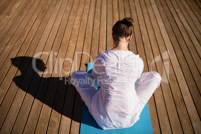 Rear view of woman practicing yoga on wooden plank