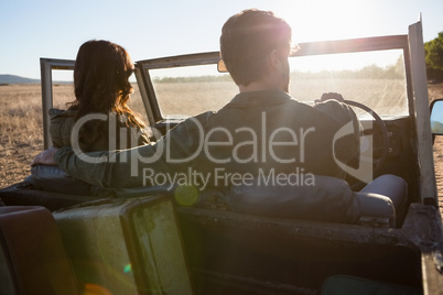 Rear view of couple in off road vehicle on sunny day