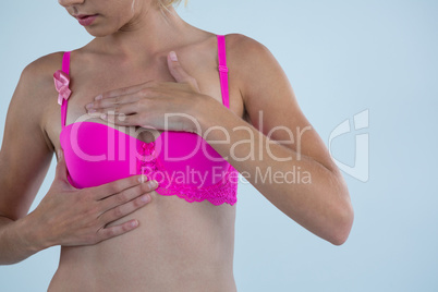 Woman with Breast Cancer Awareness ribbon checking lumps while touching breast