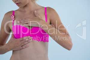 Woman with Breast Cancer Awareness ribbon checking lumps while touching breast