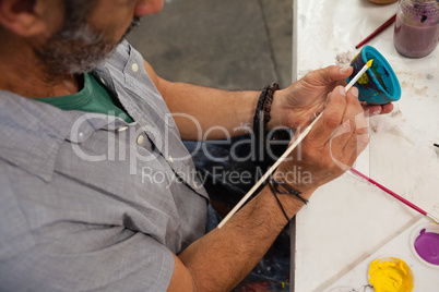 Attentive man painting bowl