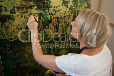 Attentive woman painting on canvas