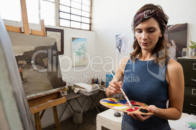 Woman painting on canvas in drawing class