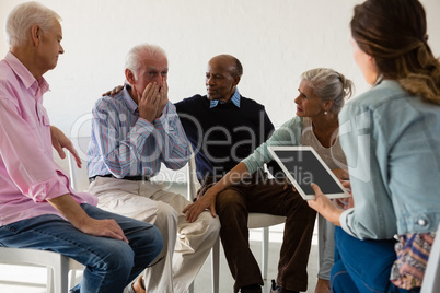 Senior friends consoling man during discussion