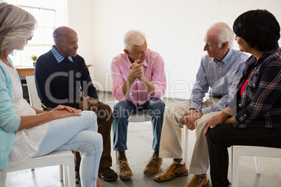 Senior people discussing while sitting on chiar