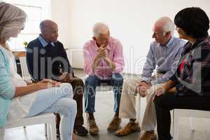 Senior people discussing while sitting on chiar