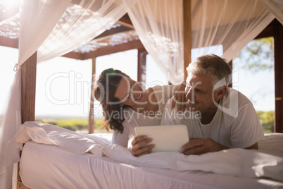 Happy couple using digital tablet on bed