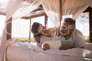 Happy couple using digital tablet on bed